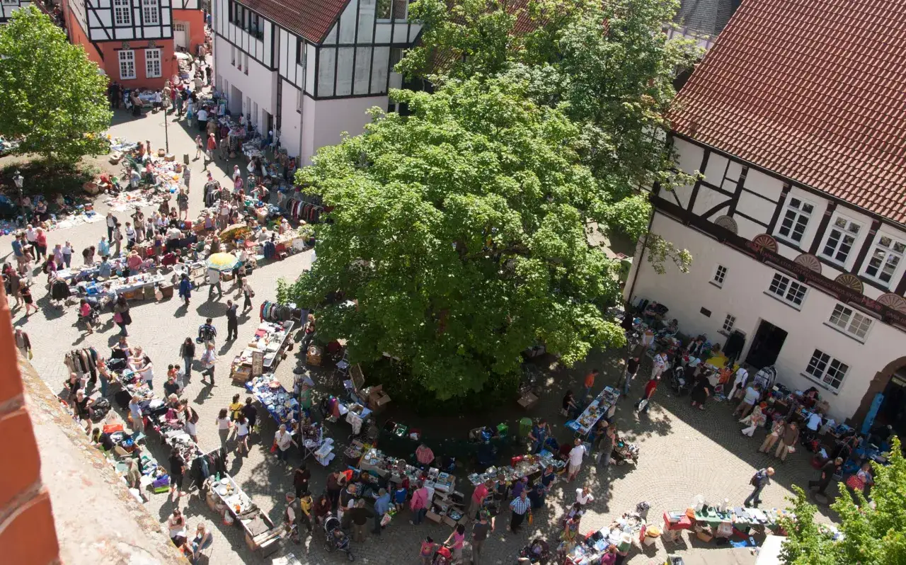 Buntes Treiben auf dem Flohmarkt Minden. Menschen schlendern zwischen Ständen mit Kleidung, Büchern und allerlei Trödel.