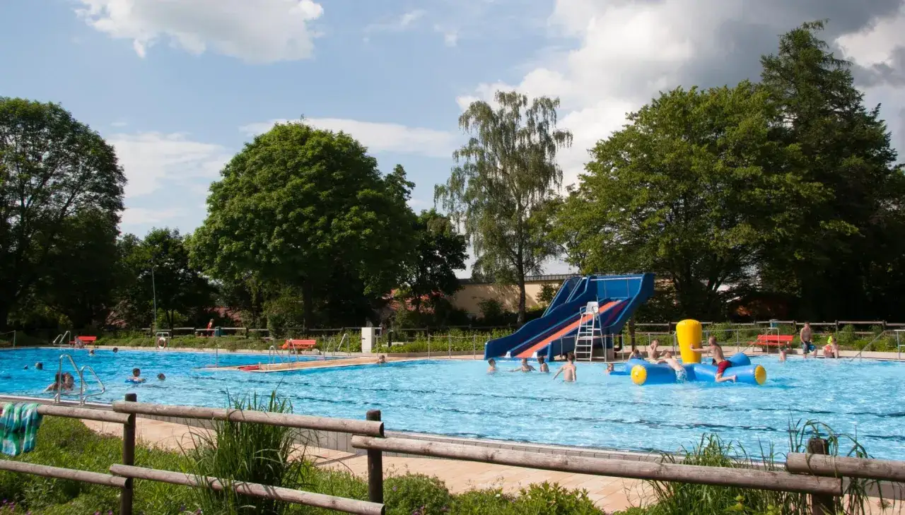 Sommerlicher Badespa&szlig; im Freibad Lahde mit Rutsche und aufblasbarem Spielzeug. Kinder planschen und genie&szlig;en die Sonne.