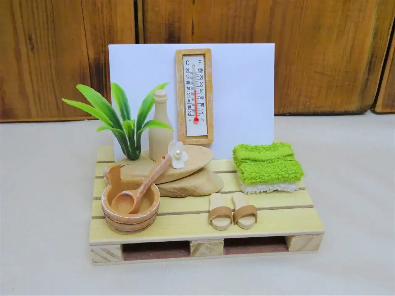 Miniatur-Sauna mit Thermometer, Aufgusseimer, Handtüchern und Pantoffeln. Perfekt als Sauna Gutschein für Entspannung.
