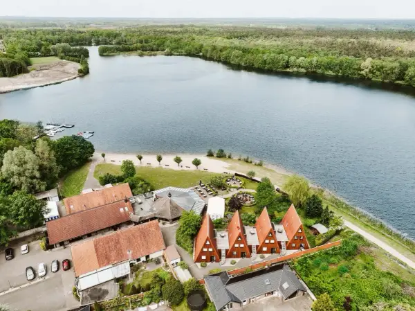 Idyllischer Seeuferbereich mit Sandstrand, Booten und Häusern. Ein perfekter Ort für einen entspannten Seeurlaub in Gronau.