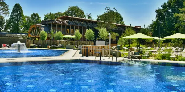 Entspannter Tag am Pool in Bad Sassendorf. Blaue Wasserflächen, Liegen unter Sonnenschirmen und ein Brunnen laden zum Verweilen ein.