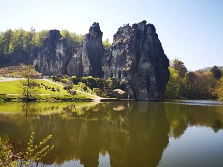 Felsformationen im Teutoburger Wald spiegeln sich in einem ruhigen See. Besucher genießen die Aussicht auf die beeindruckende Natur.
