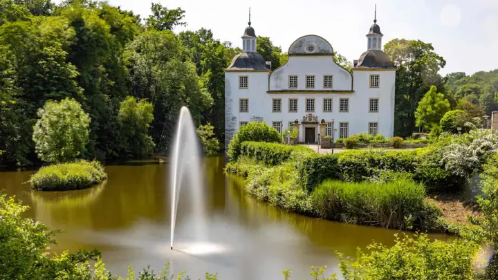 Schloss mit Wasserspielen und grüner Parkanlage, ein idyllischer Ort zum Entspannen und Genießen. Ein schönes Ziel in der Nähe von Essen Stadt.