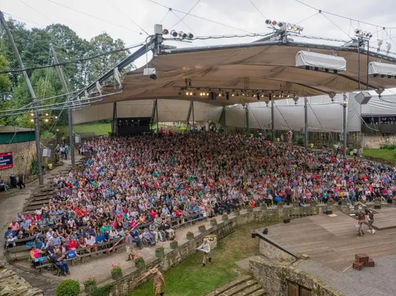Großes Freilichttheater mit vielen Zuschauern bei Tecklenburg Veranstaltungen. Ein Schauspiel wird auf der Bühne aufgeführt.